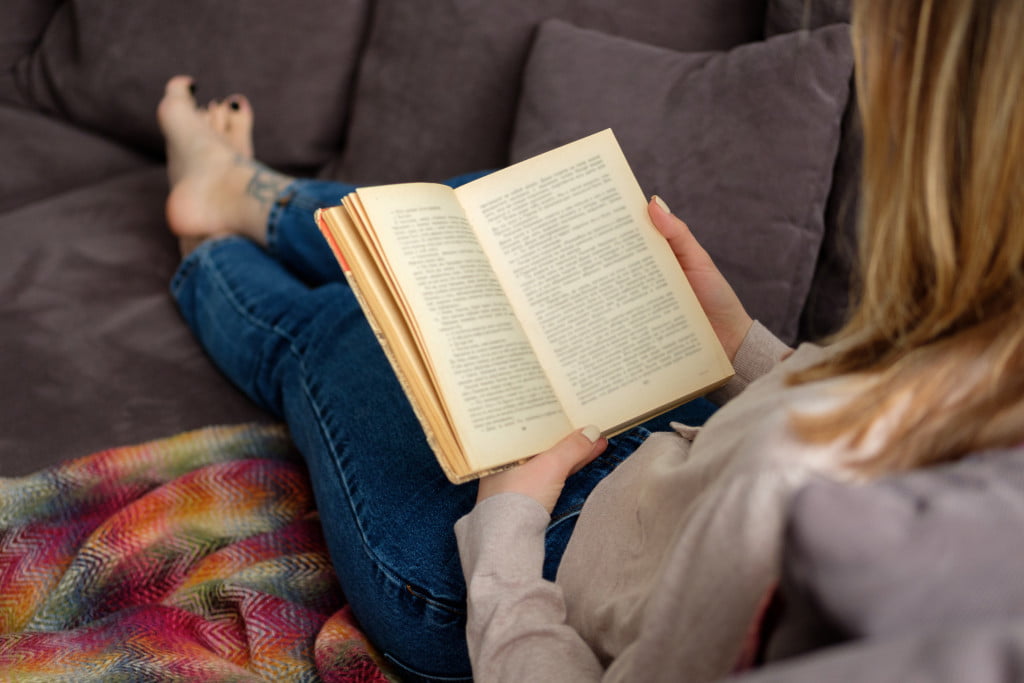 person reading a book in the sofa