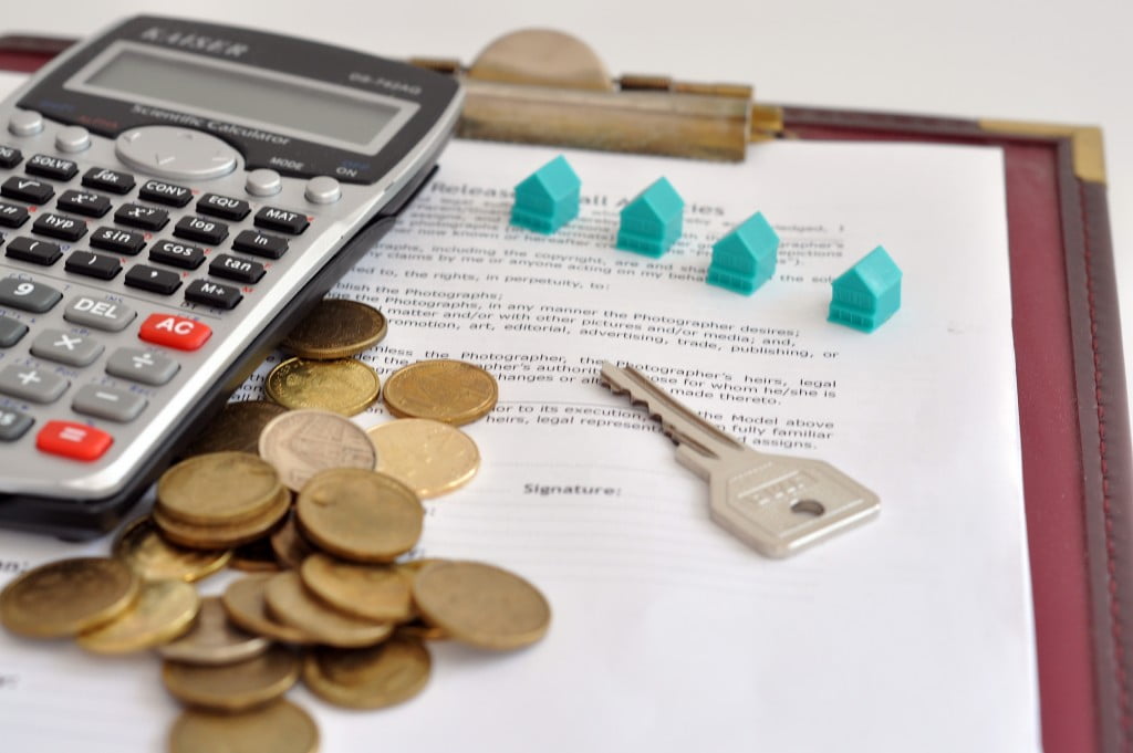 miniature homes, coins, and calculator on top of a document