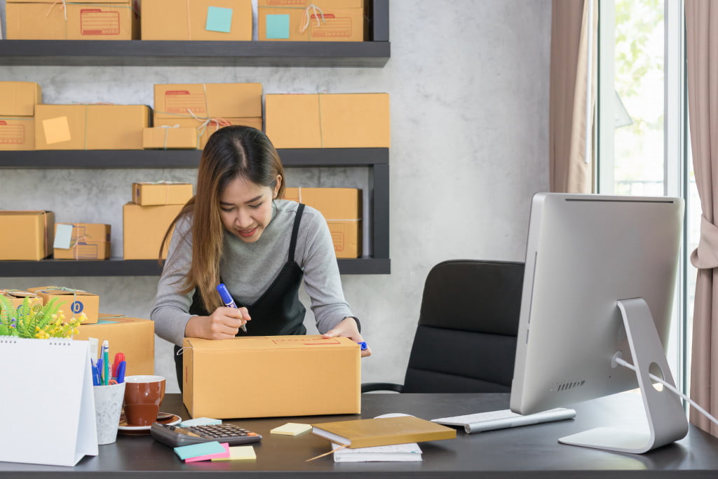 woman writing on her package to be sent to clients